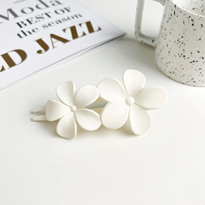 Detail of white matte double flower hair clip on a minimalist aesthetic background