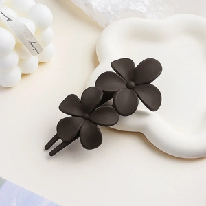 Detail of matte dark coffee floral hair clip on a white cloud porcelain plate decoration