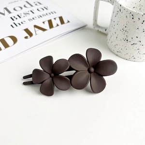 Detail view of dark brown matte floral hair clip with two elegant flowers on a desk