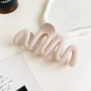 Detailed view of pink wavy matte hair claw clip on a stylish decorative tray