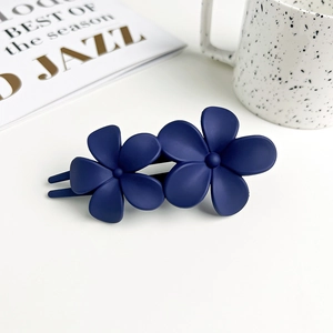 Detail shot of navy blue matte flower hair clip on a minimalist aesthetic background