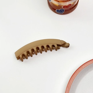 Dettaglio del fermaglio a banana kaki opaco con denti intrecciati su fondo bianco