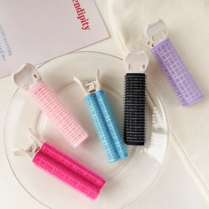 Close-up of colorful self-adhesive hair rollers in a glass bowl for volume styling