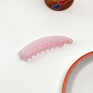 Dettaglio del fermaglio a banana rosa opaco con struttura multidente per coda di cavallo