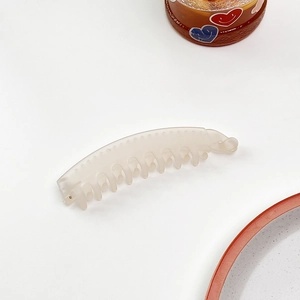 Dettaglio del fermaglio a banana crema opaco con denti curvi e chiusura a rotazione