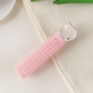 Detailed close-up of pink hair root clip showing hook-and-loop texture on fabric background