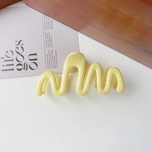 Detailed view of pale yellow wavy hair claw clip on aesthetic minimalist background