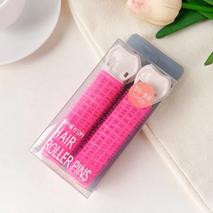 Close-up of pink hair root clips in clear packaging with elegant floral background