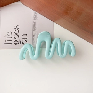 Detail view of light blue wavy hair claw clip on wooden block with aesthetic card