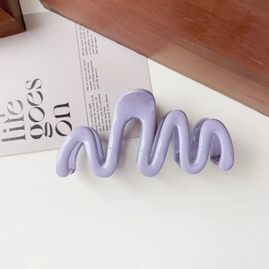 Macro detail of lilac wave-shaped claw clip made of polished premium resin material