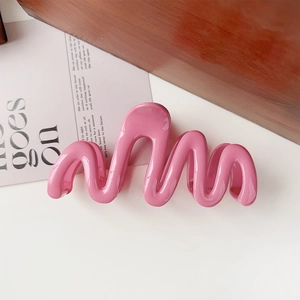 Detailed view of glossy bright pink wave-shaped hair claw clip on a white background
