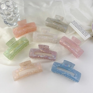 Detailed macro view of eight colorful acrylic hair claws with marble textures on satin