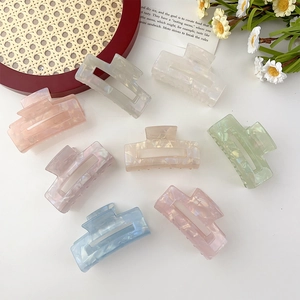 Detailed macro view of large pastel acetate hair claws with marble texture and pearl finish