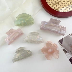 Macro shot of colorful pearlescent acrylic hair clips on a woven tray with silk