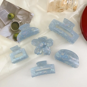 Set of six light blue marble pattern acrylic hair claws on a luxury silk background