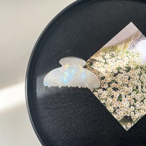 Detail of pearlescent white acrylic claw clip on a tray with floral card decoration