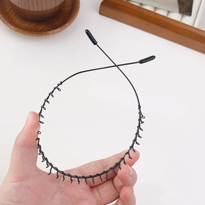 Détail du serre-tête ondulé en métal noir avec dents fines et embouts en silicone