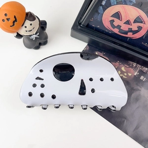 Dettaglio della molletta per capelli Halloween con pois neri su superficie bianca