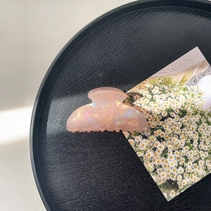 Detailed view of pink iridescent acrylic hair claw clip with mother of pearl texture