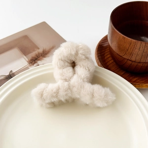 Détail d'une pince à cheveux en peluche blanc crème sur un plateau pour une coiffure d'automne