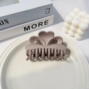Nahaufnahme einer staubrosa matten Herz-Haarklammer auf einem minimalistischen Display