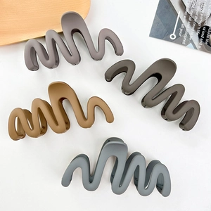Set of four matte wavy hair claws in taupe, olive, camel and blue on a white surface