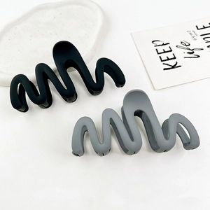 Macro shot of two large wavy matte hair claws in black and dark grey colors