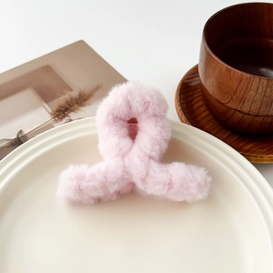 Détail d'une pince à cheveux en peluche rose doux posée sur un plateau en céramique