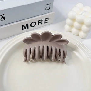 Detail der großen matten kaffeebraunen Haarklammer im Blüten-Design auf Keramikteller