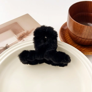 Détail de la pince à cheveux noire en peluche sur assiette blanche, ambiance cocooning