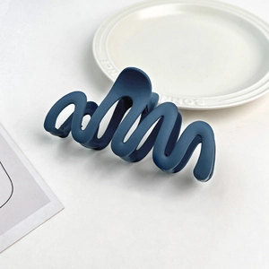 Macro detail of dark blue matte wave hair claw clip on elegant white ceramic plate