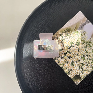 Detail of an iridescent acrylic hair claw clip with a pearlescent finish on a tray