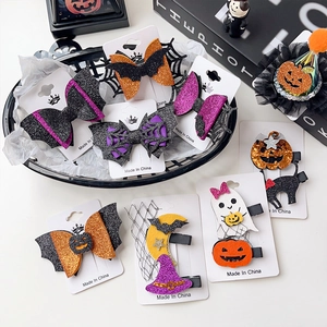 Detail of Halloween hair clips featuring glitter pumpkins, ghosts, and bats on black clips