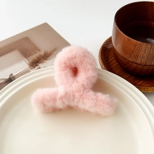 Gros plan d'une pince à cheveux en peluche rose doux sur une assiette en céramique blanche