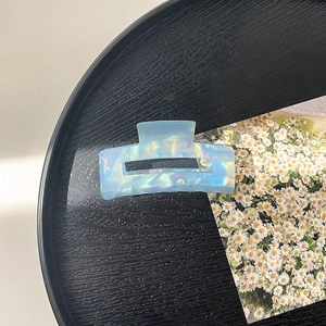 Close-up of geometric rectangle hair claw clip with iridescent blue pearlescent texture