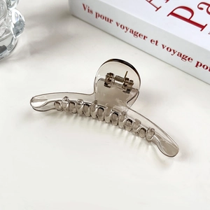 Gros plan détaillé d'une grande pince à cheveux ambre translucide avec ressort en métal