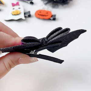 Close-up of black bow hair clip with shimmering texture and metal clip detail