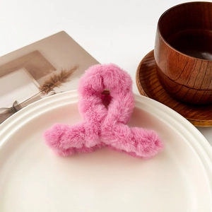 Détail d'une grande pince à cheveux rose en peluche avec une texture douce et velue