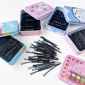 Dettaglio di forcine per capelli nere in varie scatole di latta con decorazioni a cartoni