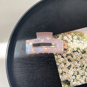 Detail of holographic pink acetate hair claw clip with pearlescent finish and metal spring