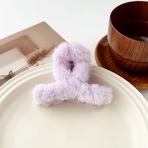 Gros plan sur la pince à cheveux en peluche lavande avec texture douce sur assiette