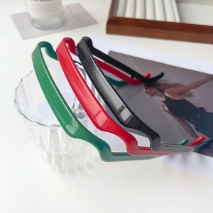 Détail de serre-têtes ondulés en résine noir, rouge et vert posés sur un verre