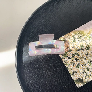 Detail of square acetate hair claw clip with iridescent pearlescent finish on a tray