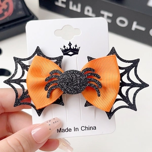 Detail of Halloween bow hair clip featuring black spider and orange ribbon on card