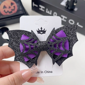 Detail of glittery bat hair clip with purple ribbon and spider web cutout design