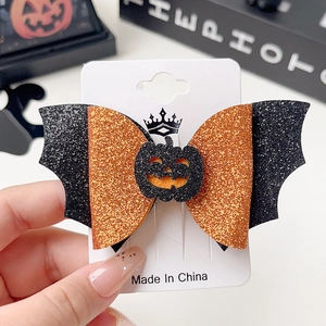 Detail of Halloween bow hair clip with orange sequins, bat wings and pumpkin face charm
