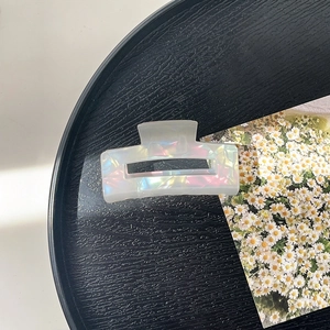 Close-up of a rectangular hollow hair claw clip with a pearlescent iridescent finish