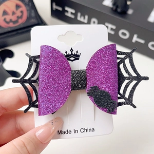 Detail of Halloween hair clip with purple sequin bow and black spider on display card