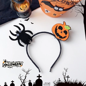 Detail view of Halloween headband with orange smiling pumpkin and fuzzy black spider decor