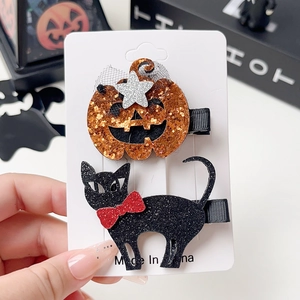 Detail of Halloween hair clips with glittery pumpkin and cat designs on white card